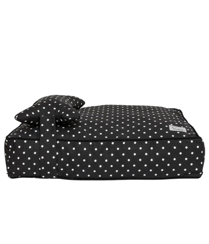 Cuccia letto per cani nero con pois bianchi e cuscino a forma di osso, vista laterale con sfondo bianco.
