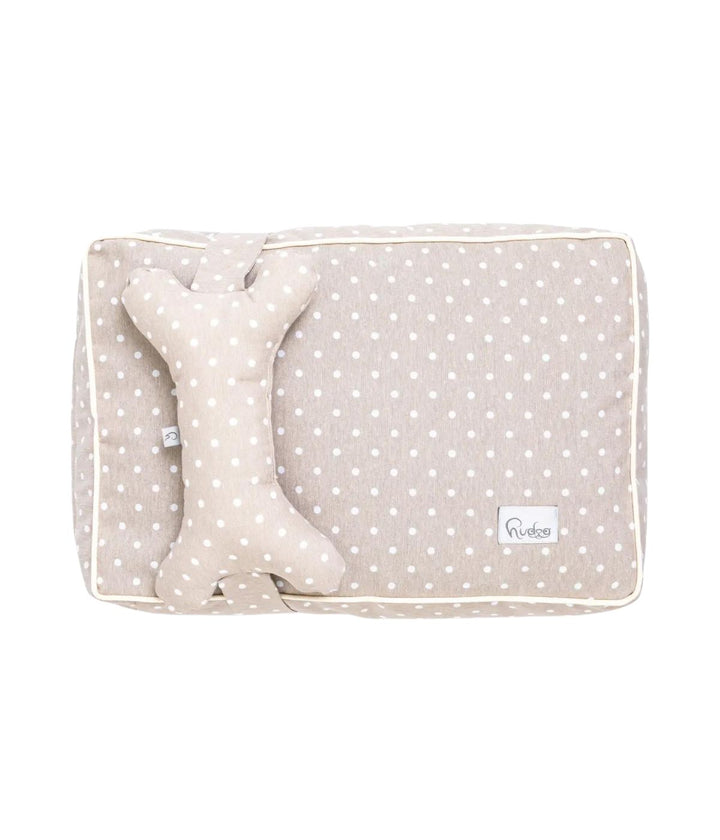 Cuccia letto per cani beige con pois bianchi e cuscino a forma di osso, vista dall'alto con sfondo bianco.