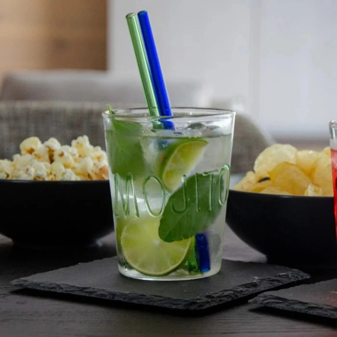 Bicchiere mojito con cannucce su piatto lavagna nero. Tavolo con stuzzichini.
