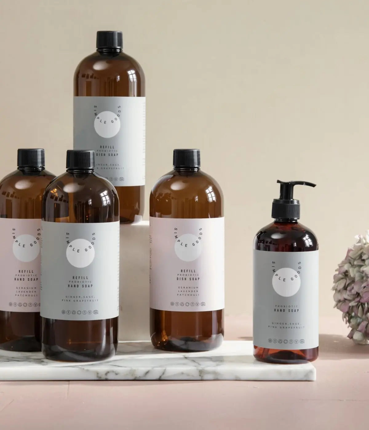 4 Bottiglie refill grandi e un despencer sapone. Etichette rosa e verdi. Scritte nere. Sfondo marmo