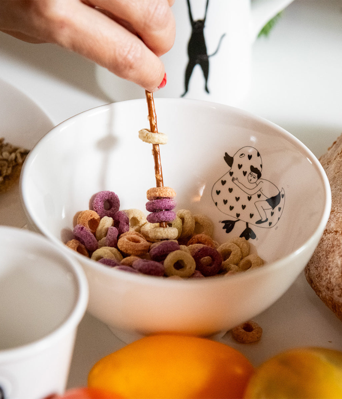 Ciotola bianca con cereali colorati dentro. Disegno papera e uomo nero e bianco. Sfondo tavola.