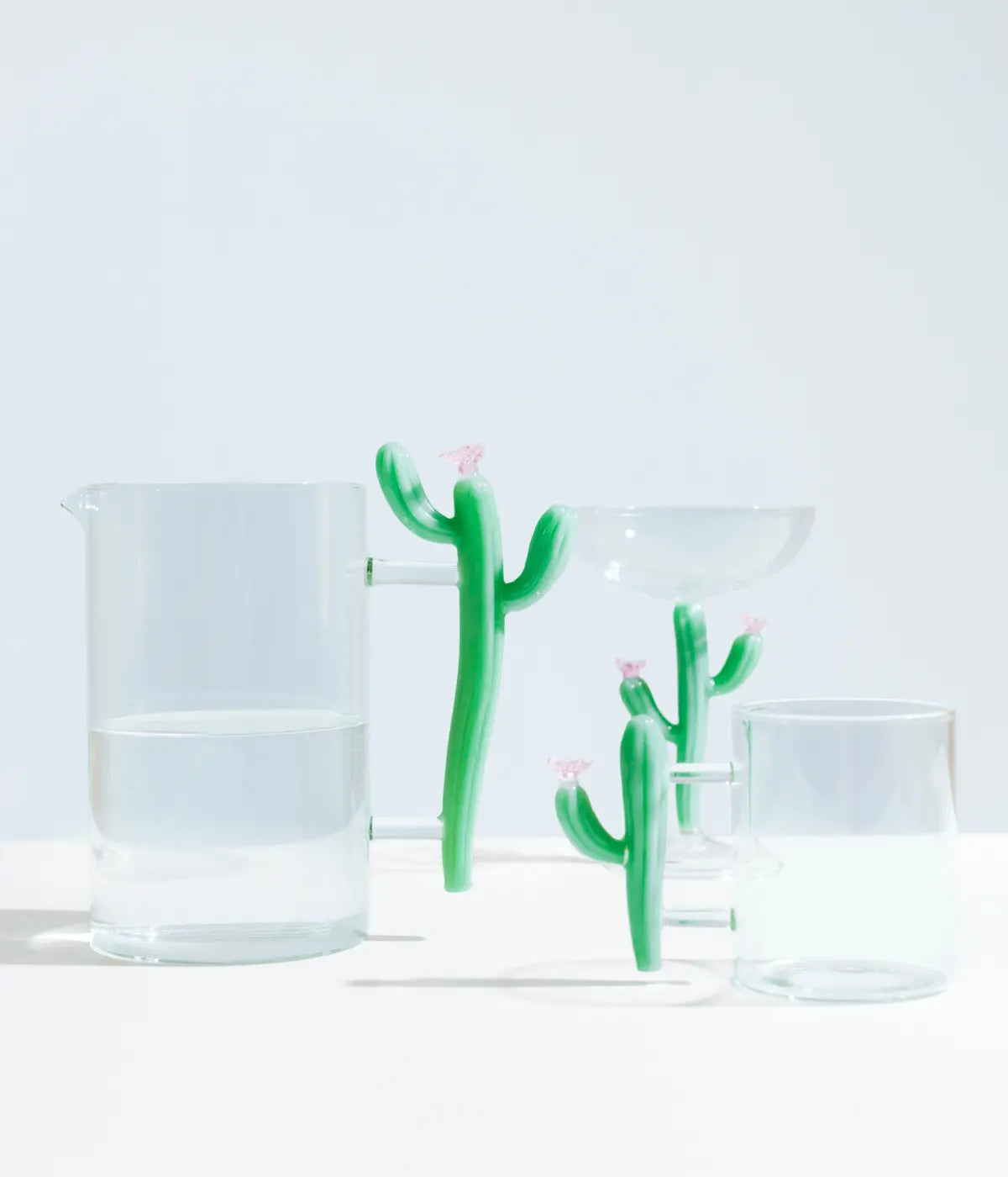 Brocca, tazza, calice in vetro con manici a forma di cactus verde opaco e fiore rosa. Sfondo bianco