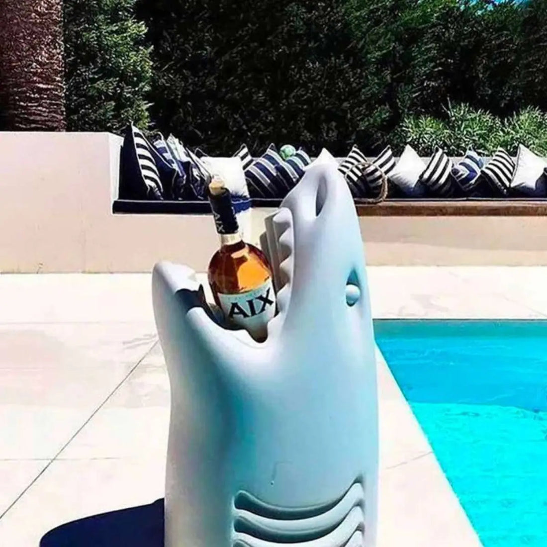 Squalo rinfrescatone porta bottiglie a bordo piscina con sullo sfondo alberi 