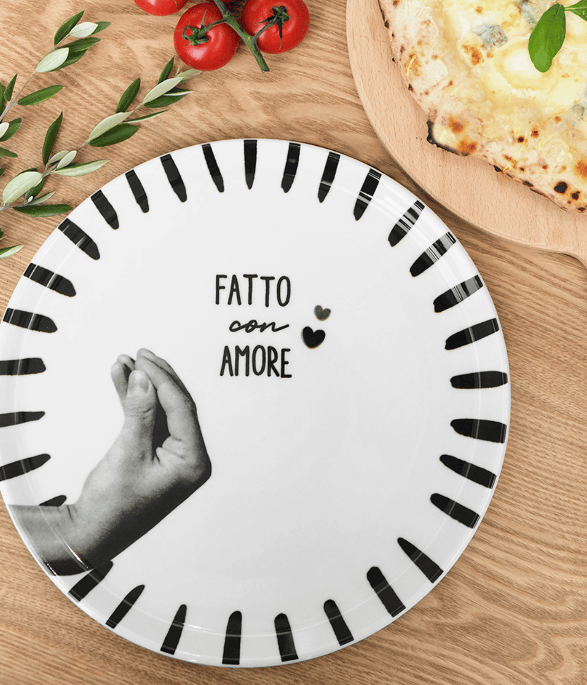 Piatto bianco con bordo decorato nero. Mano grigia e scritta centrale. Sfondo marrone con alimenti.