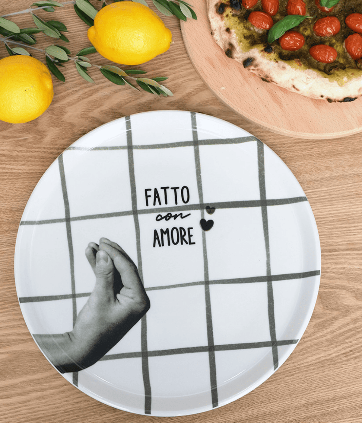 Piatto bianco con mano grigia e righe grigie, scritta e cuori neri. Sfondo tavolo in legno, alimenti.