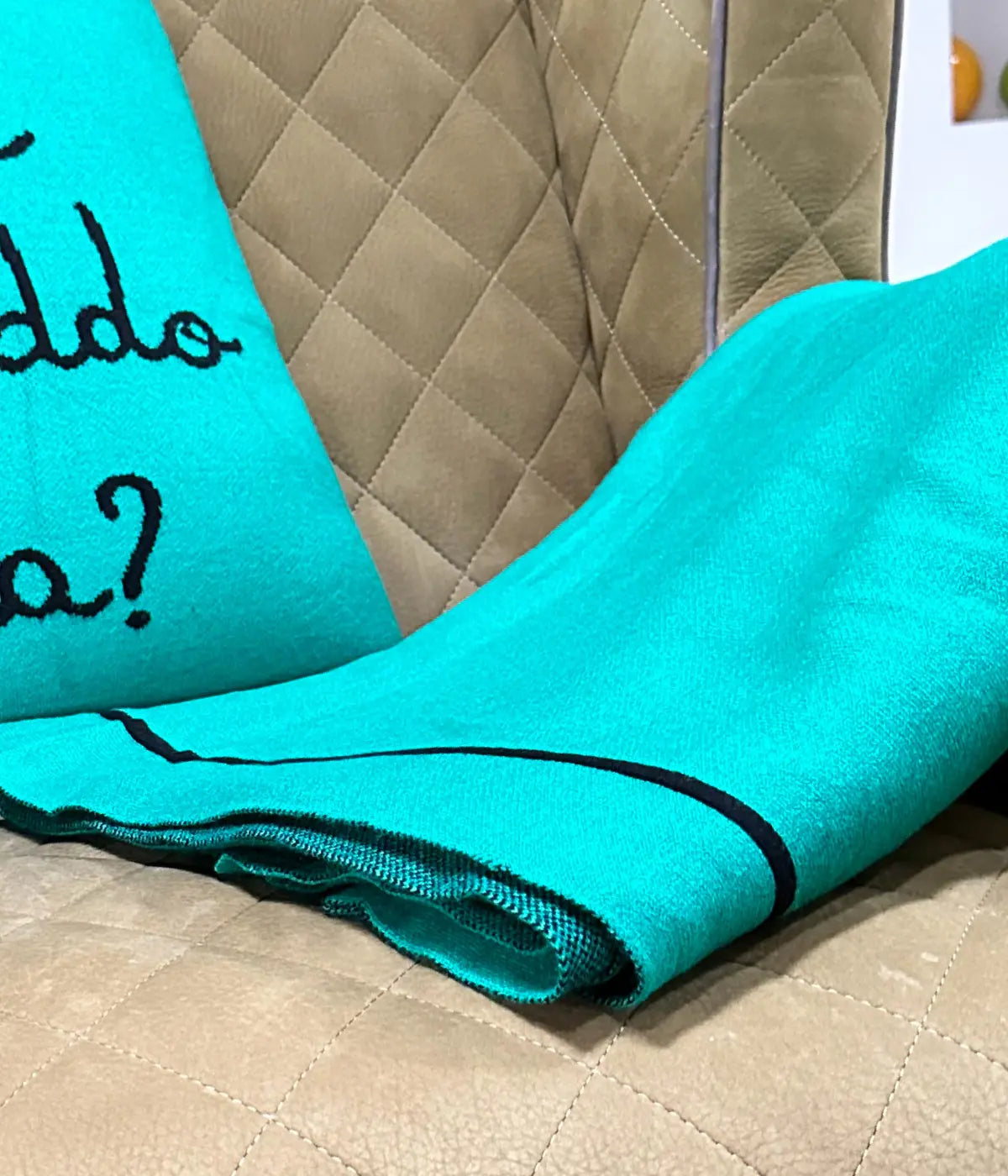 Una poltrona beige con sopra coperta e cuscino verdi abbinati. Scritta ma che freddo fa? 