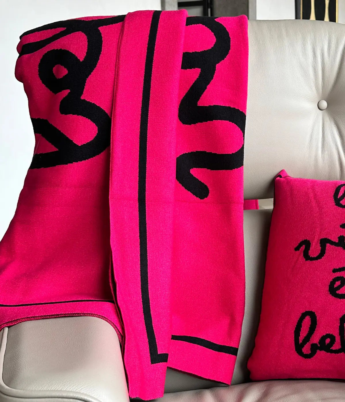 Poltrona grigia con sopra coperta e cuscino fuxia abbinati. Scritta la vita è bella