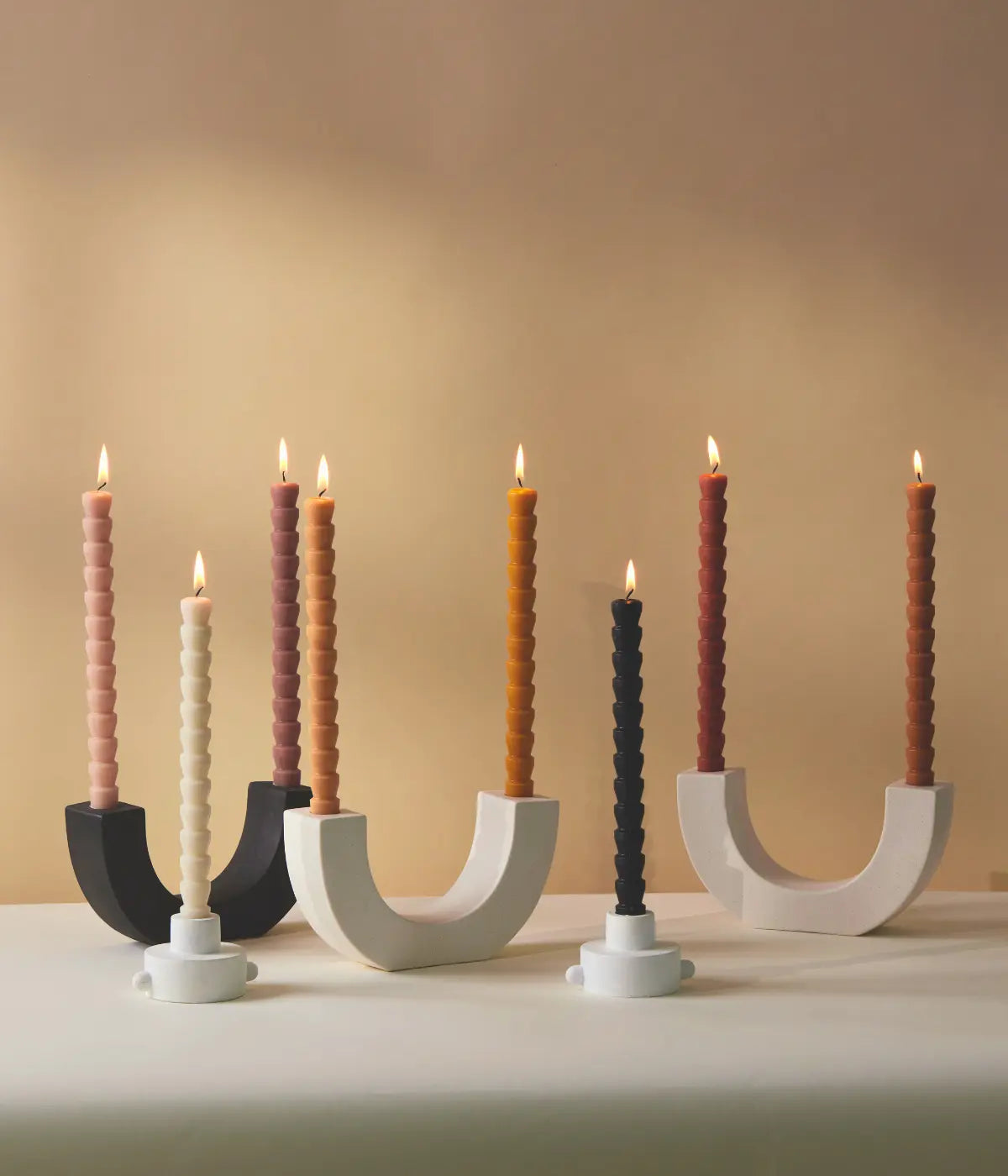 Portacandele a mezzaluna bianchi e neri. Candele bianche, nere, colorate. Forma conica. Fondo tavolo