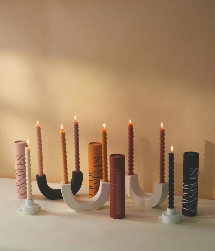 Portacandele a mezzaluna bianchi e neri. Candele bianche, nere, colorate. Confezioni. Sfondo tavolo