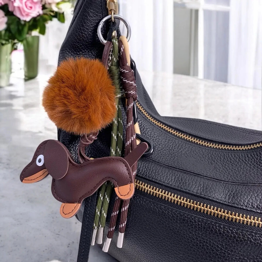 portachiavi con bassotto e pompon attaccato a borsa, su tavolo