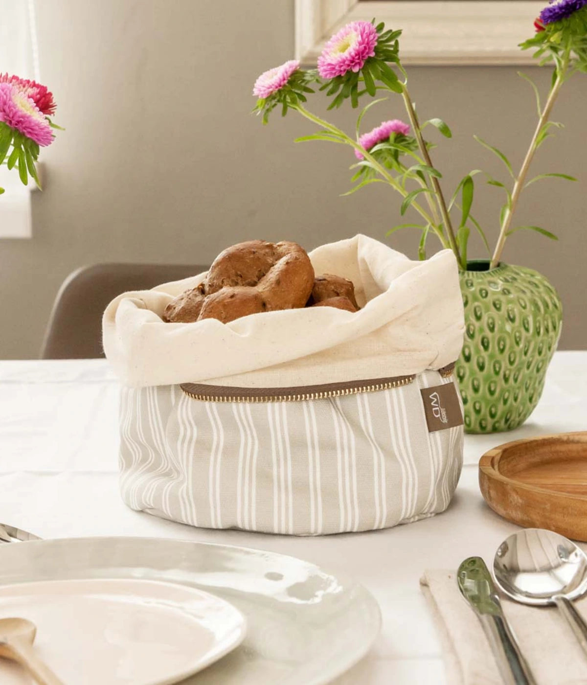 Un sacchetto portapane gessato grigio con cerniera e pane dentro. Sfondo tavola con tovaglia grigia.