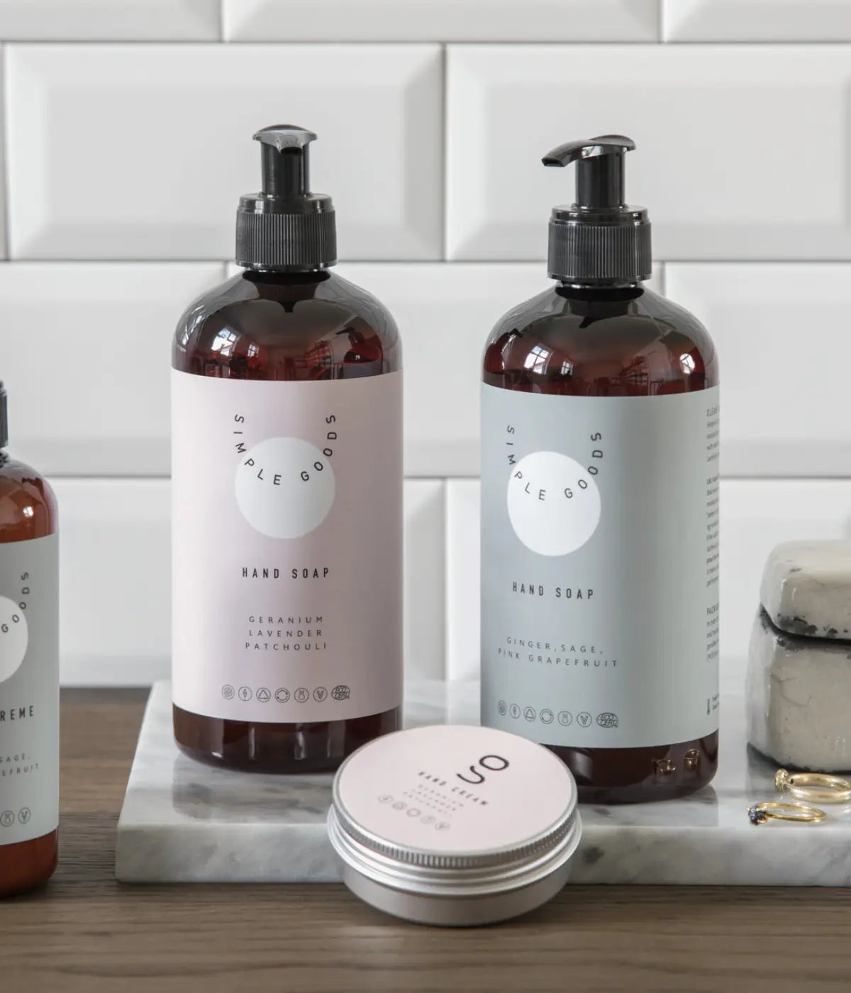 Due porta sapone marroni con etichette una rosa, una verde. Scritta hand soap. Sfondo bagno.