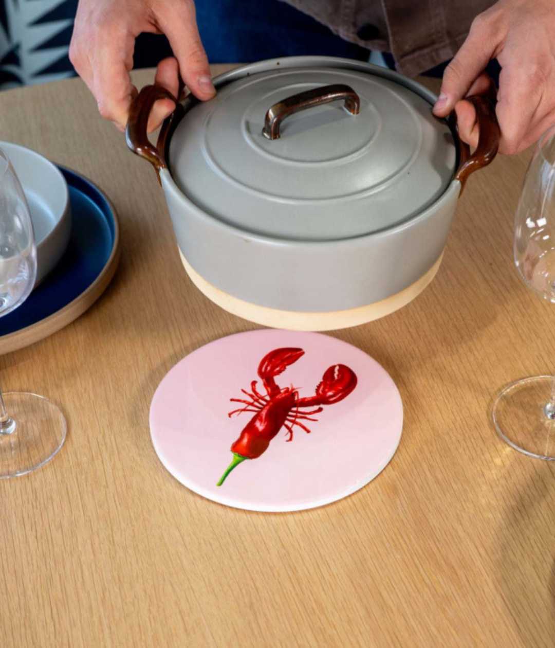 Sottopentola rosa con aragosta mixata con peperoncino rossa. Sfondo tavolo marrone con pentola