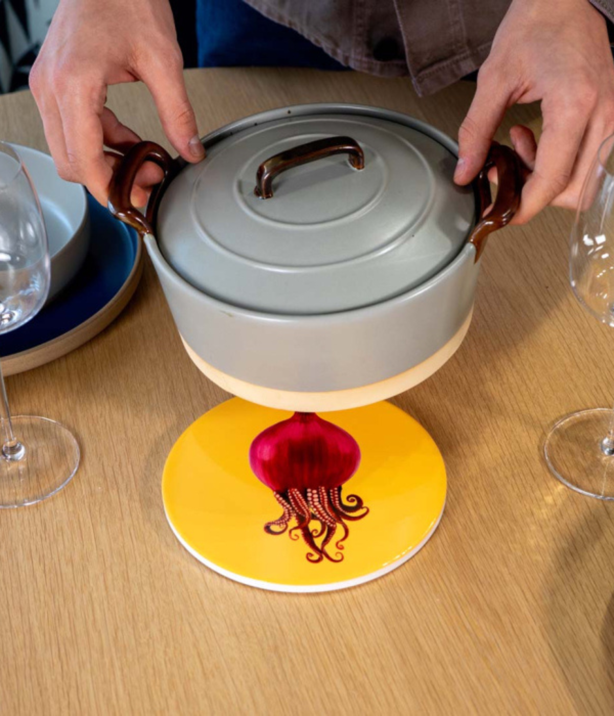 Sottopentola giallo con polipo mixato con cipolla rossa. Sfondo tavolo marrone con pentola