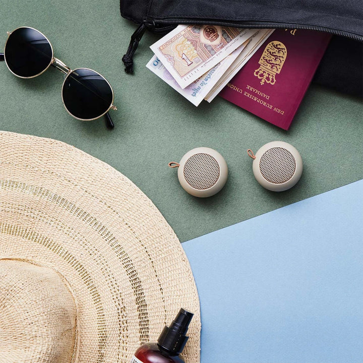 due mini casse audio bluetooth di colore tortora su tavolo verde.