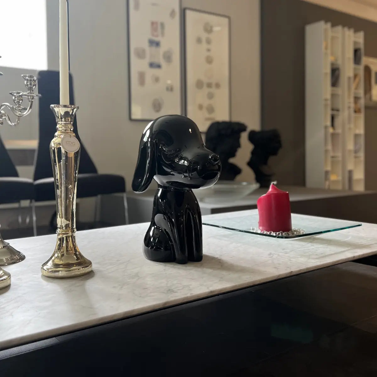 Statua Arturo nera appoggiata su mobile in marmo bianco. Sfondo quadri, statue e candele