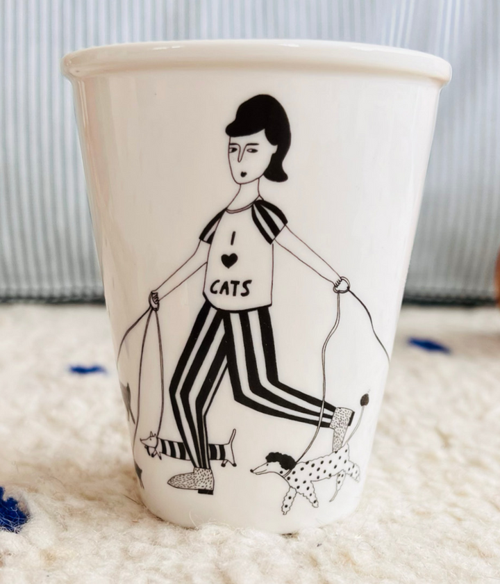 Tazza bianca disegno donna che tiene al guinzaglio i suoi cani. Maglietta con scritta. Sfondo tappeto
