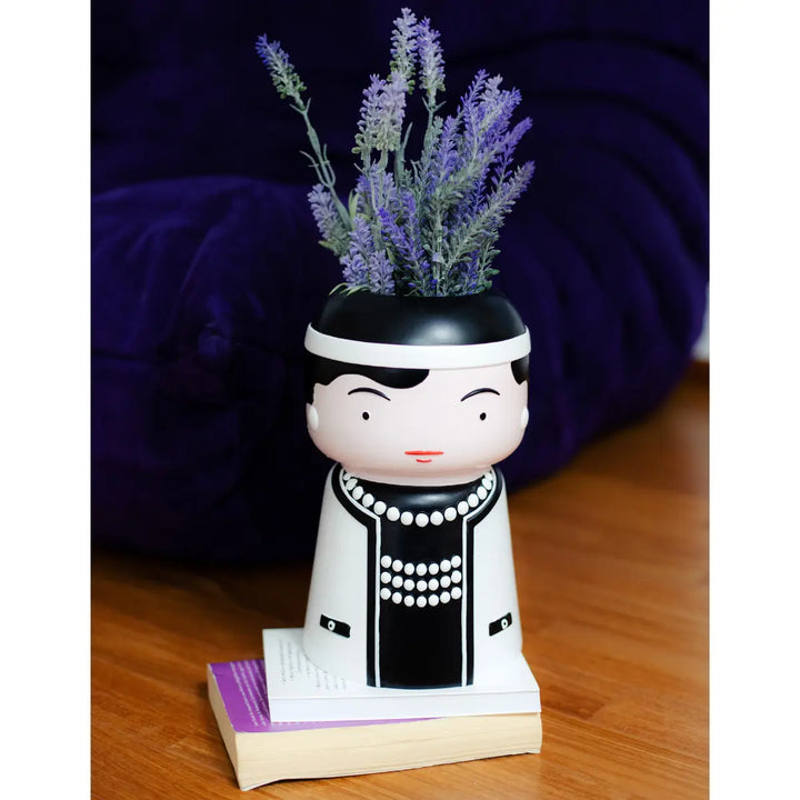 Vaso Icon raffigurante Coco Chanel con all'interno rami di lavanda. Appoggiato su libri