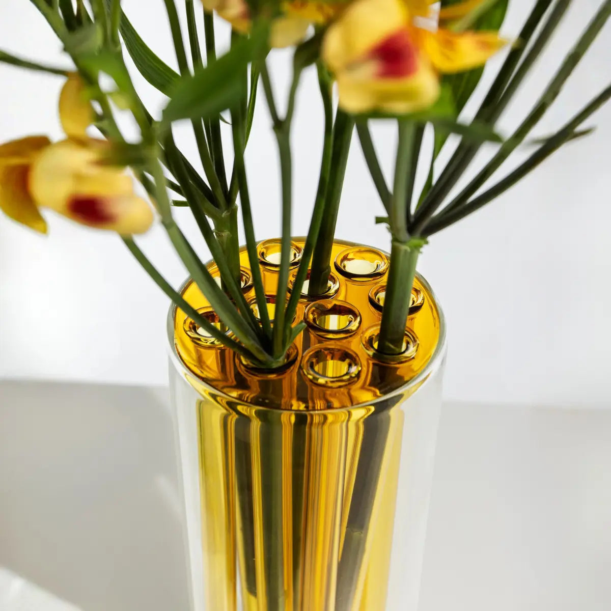Dettaglio vaso trasparente con inserti amovibili in vetro colorato giallo per fiori a stelo lungo