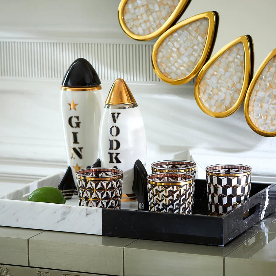Due decanter scritta Vodka e Gin a forma di razzo e bicchieri appoggiati su vassoio nero e bianco.
