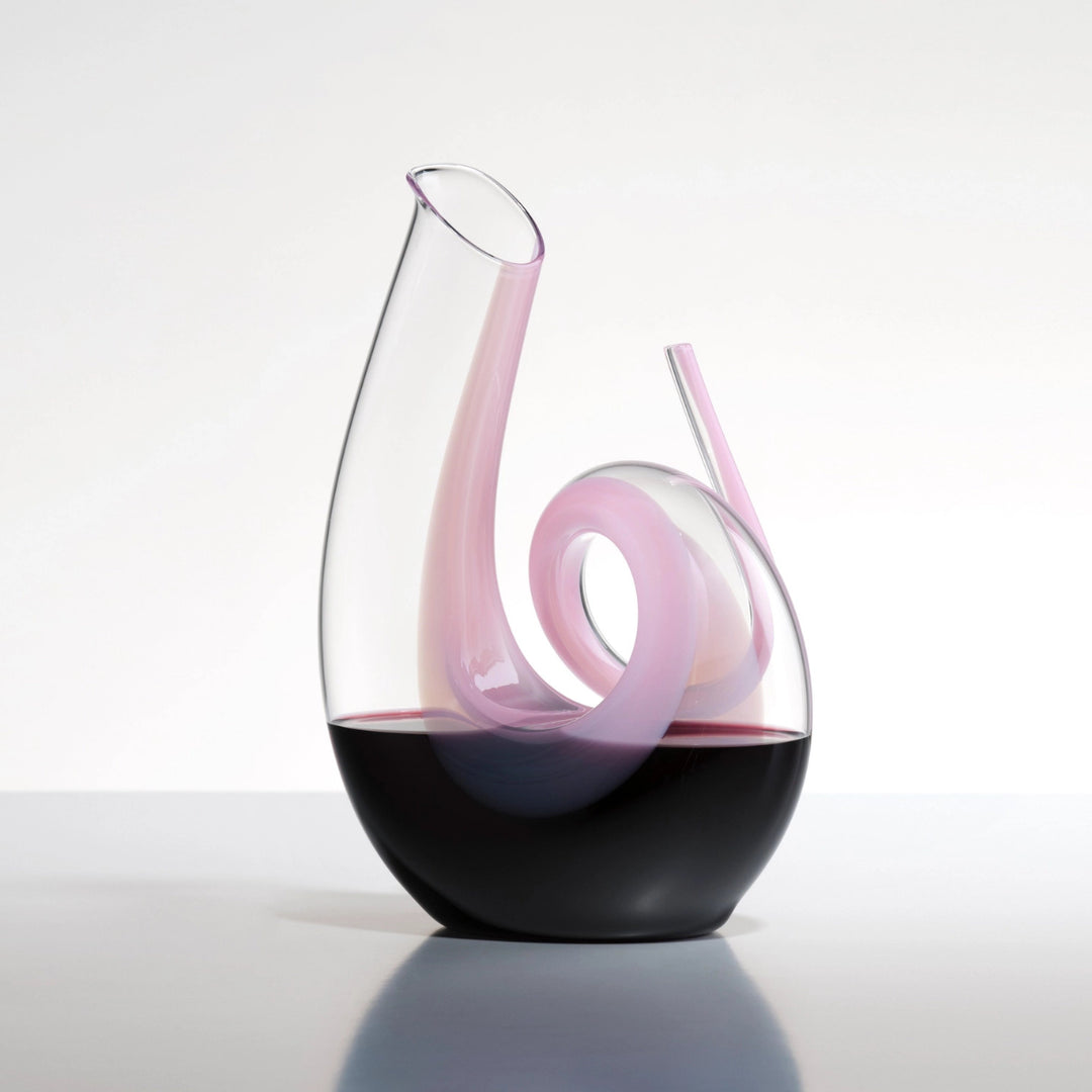 decanter rosa riedel riempito di vino, appoggiato su un piano