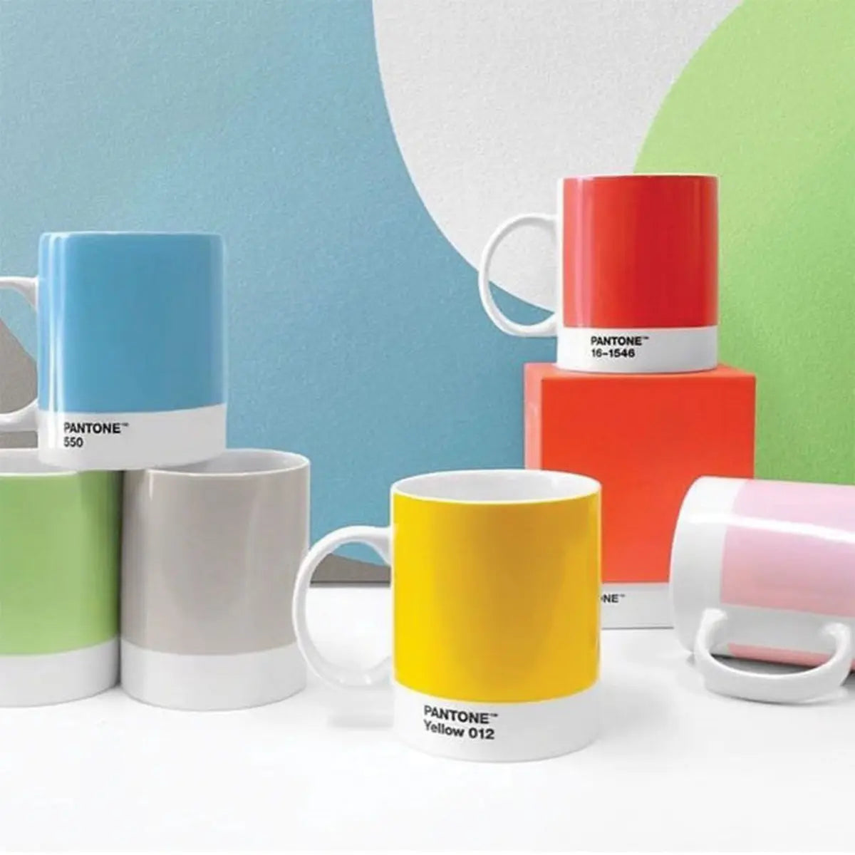 6 tazzine della linea pantone appoggiate su tavolo bianco con sfondo parete colorata