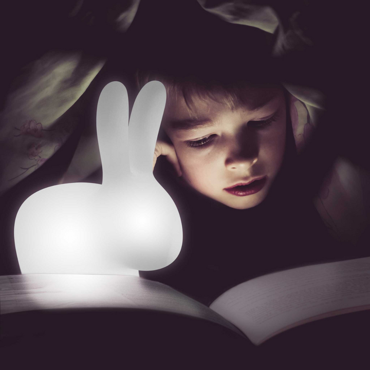 bambino sotto la coperta mentre legge con lampada illuminata