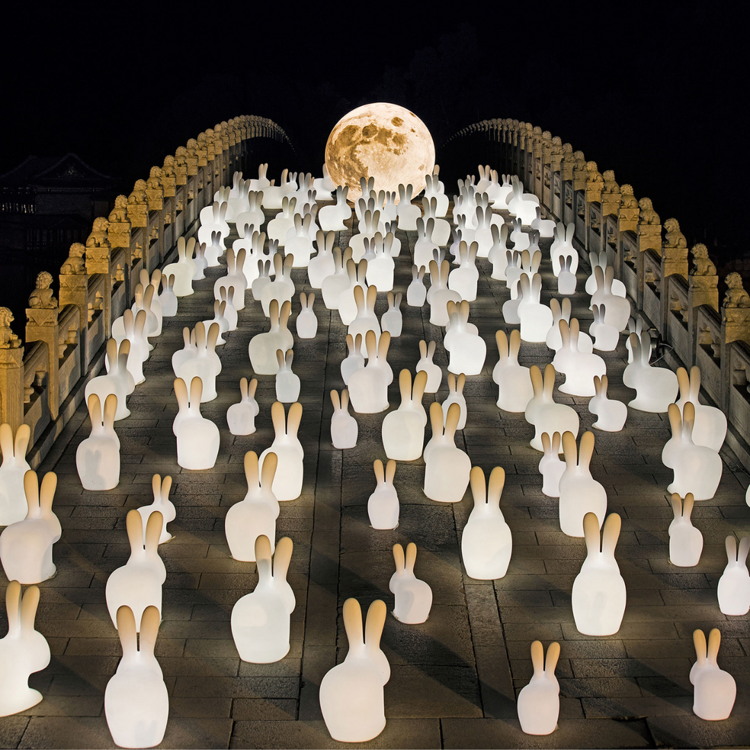 Tante lampade  a forma di coniglio accese, su ponte con luna su sfondo