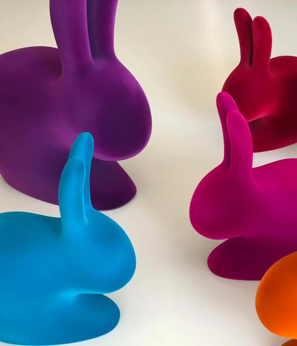 Sedie a forma di coniglio in velluto viola, arancione, turchese, fuxia, rosso. Sfondo bianco
