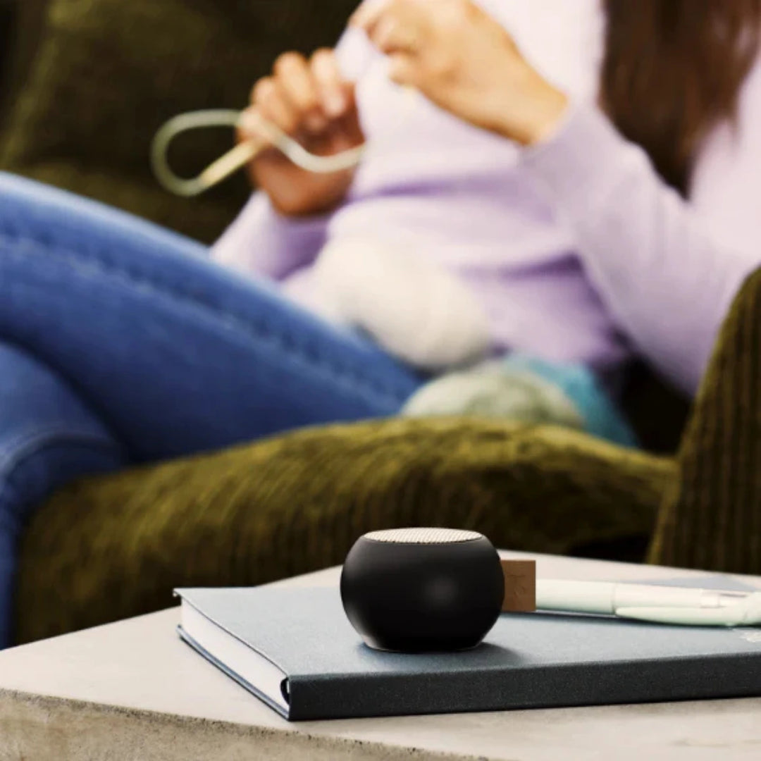 mini cassa audio portatile nera, su libro. Donna sullo sfondo.