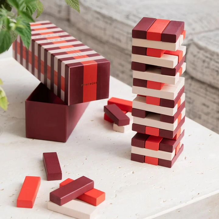 Scatola gioco, torre  e pezzi in legno appoggiati su tavolo bianco