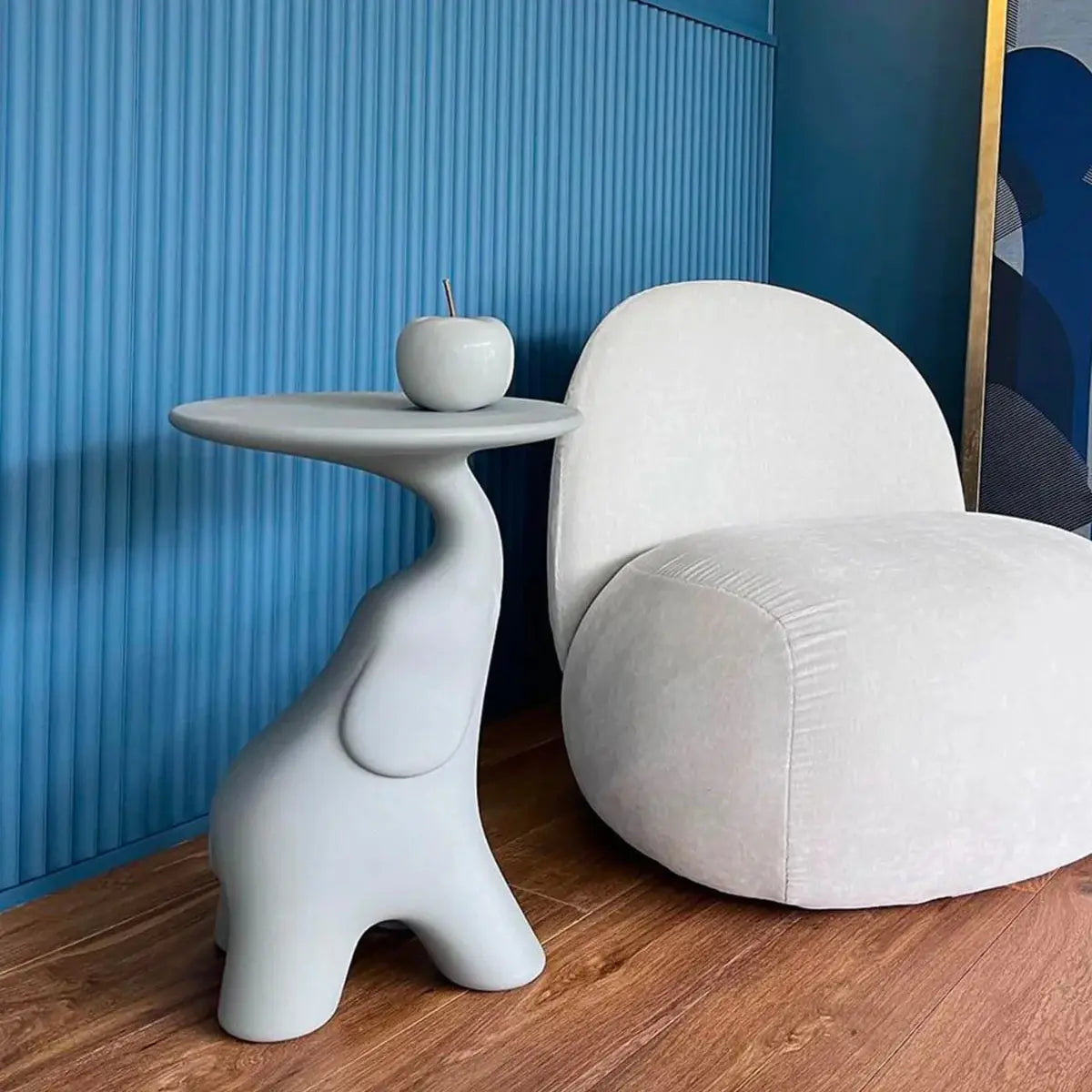 Tavolino a forma di elefante con piano rotondo di colore bianco di Qeeboo posizionato in un salotto con le pareti blu e una poltrona bianca