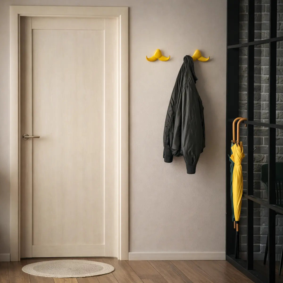 Ingresso di una casa con due appendiabiti baffo di Slide appesi accanto alla porta. Su uno degli appendiabiti è appesa una giacca nera.