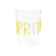 Bicchiere di vetro trasparente con scritta gialla in rilievo "Spritz". Sfondo bianco