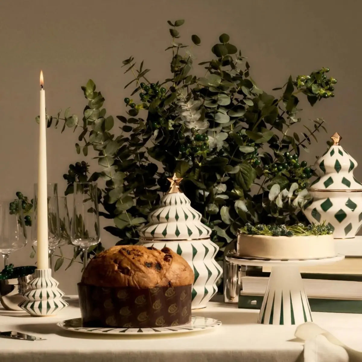 Biscottiera natalizia di Alessi ispirata alla forma dell'albero di natale tenuta in mano 