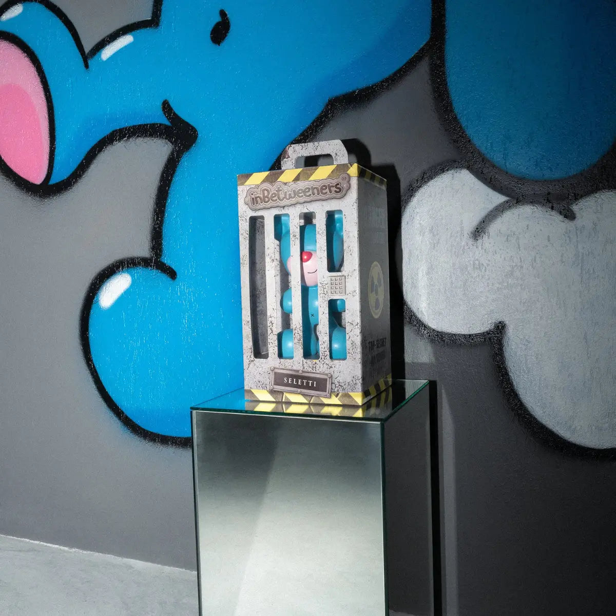 Confezione dell'art toy Blue Bear che ricorda una prigione. Nello sfondo graffiti