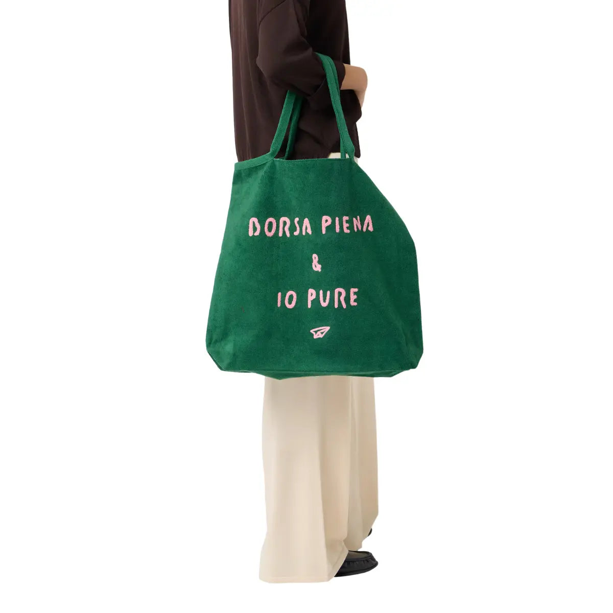 Donna che tiene la borsa verde con scritta rosa "borsa piena e io pure". Sfondo bianco 