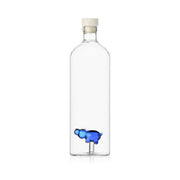 Bottiglia di vetro con all'interno un ippopotamo blu lavorato a lume. Sfondo bianco