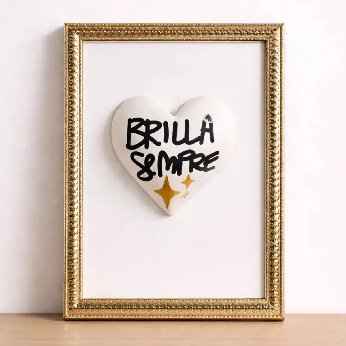 Quadretto CuoreAmore fatto a mano in Italia. Ha una cornice oro e un cuore in ceramica bianco con una scritta  