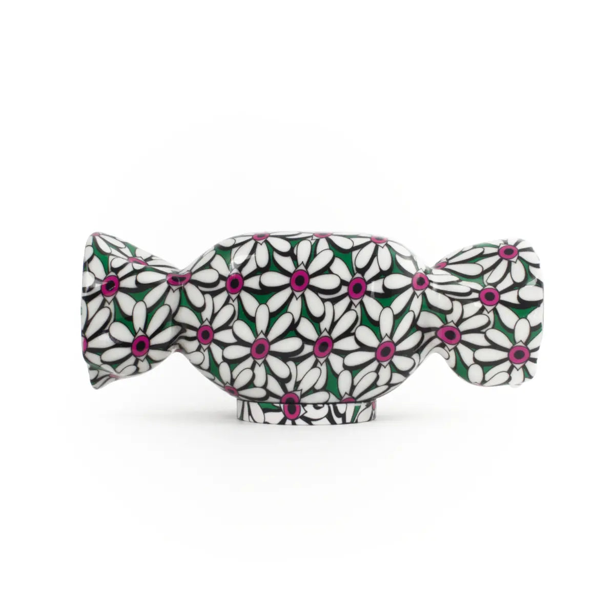 Lampada da tavolo a forma di caramella con base verde e fantasia con fiori bianchi con al centro degli occhi fucsia. Sfondo bianco 