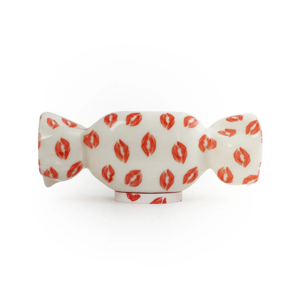 Lampada da tavolo a forma di caramella con base bianca e fantasia con baci rossi. Sfondo bianco 