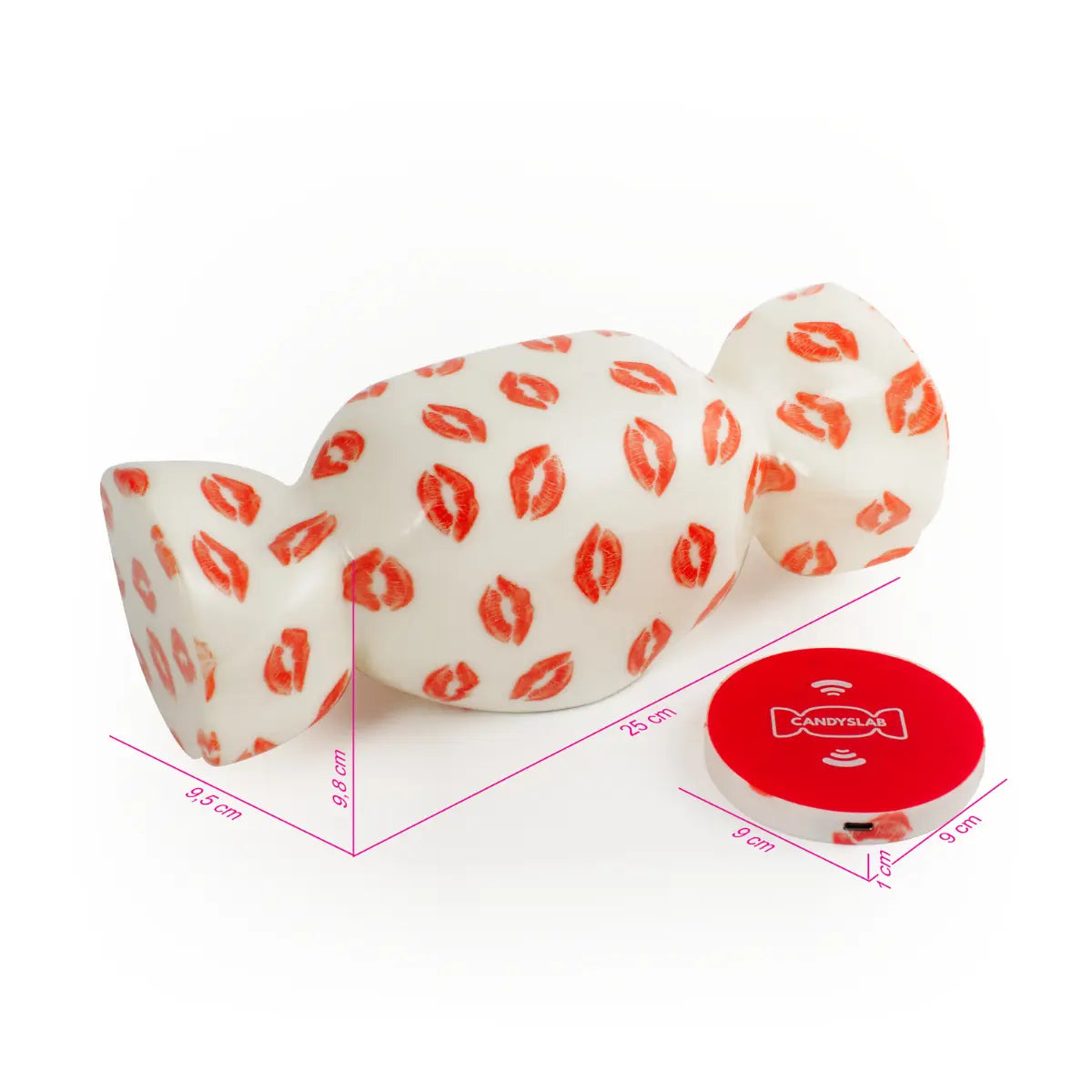 Lampada da tavolo a forma di caramella con base bianca e fantasia con baci rossi. Accanto appoggiata base di ricarica wireless. Le misure degli elementi sono segnate in fucsia. Sfondo bianco