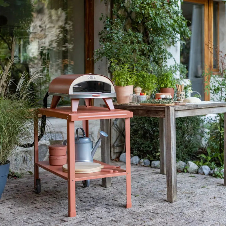 Carrello da servizio con due ruote color terracotta in un giardino
