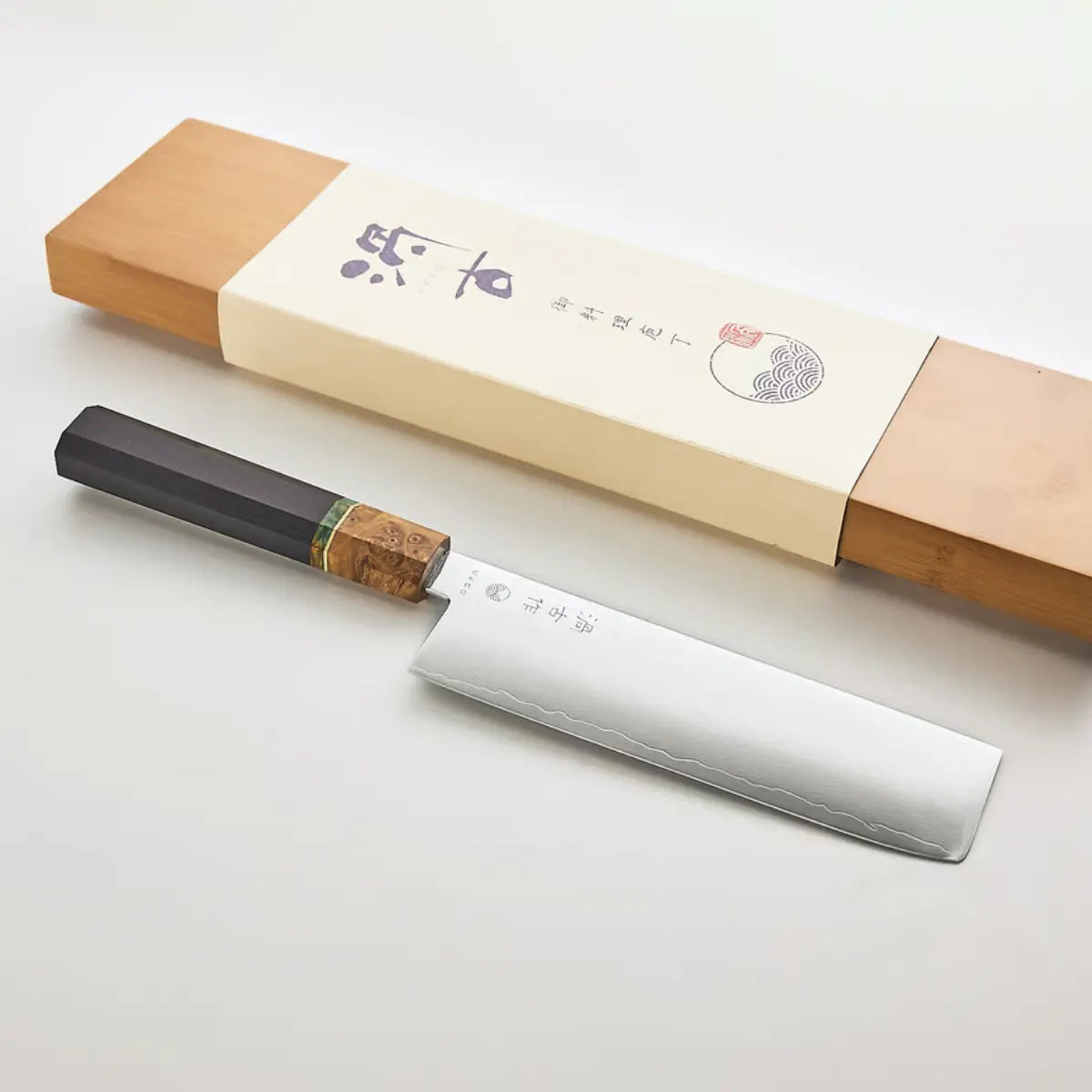 Coltello con lama rettangolare e scritta e lavorazione damascata, manico nero con dettaglio verde e color legno.