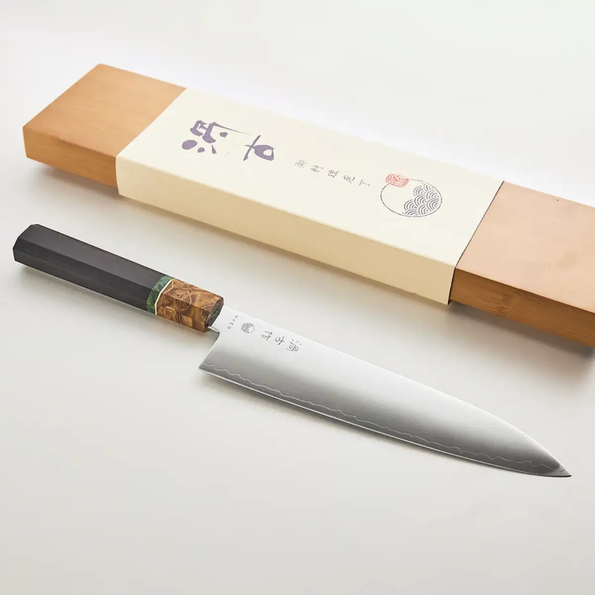 Coltello con lavorazione damascata, manico nero con dettaglio verde e color legno.
Coltello_Gyuto_Uzco