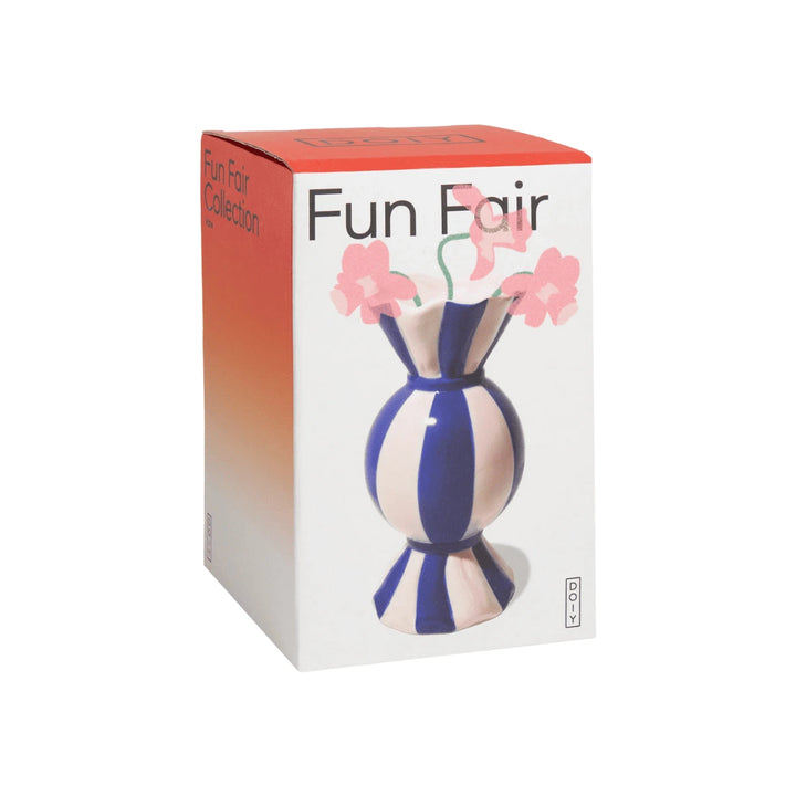 Scatola bianca e rossa con scritta funfair nera e vaso a forma di caramella blu con fiori rosa.