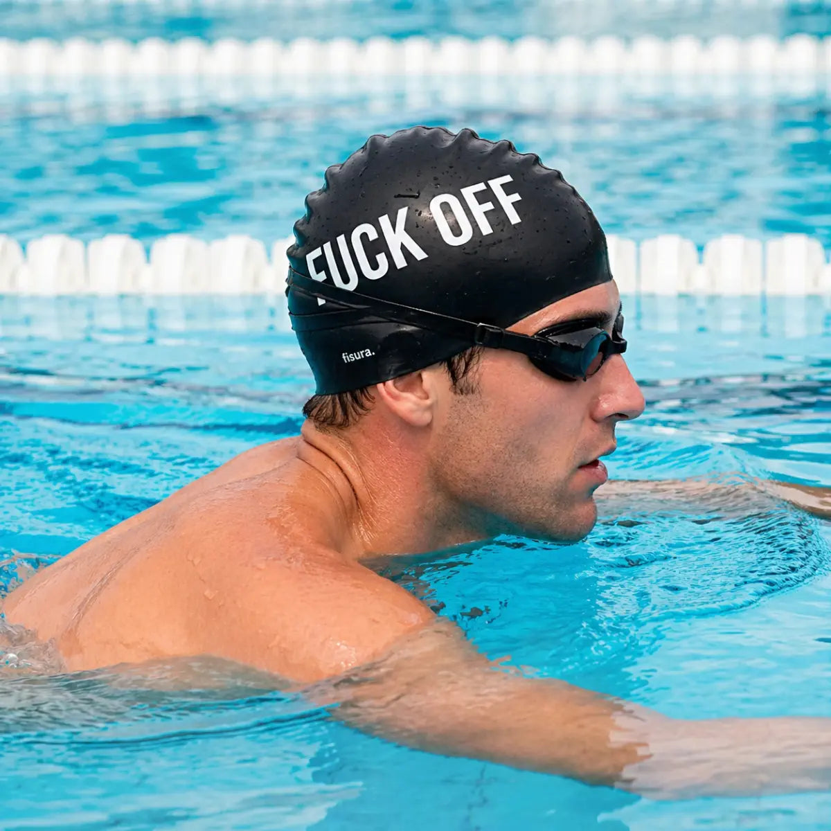 Ragazzo che indossa la cuffia da piscina nera in silicone con scritta bianca "Fuck off"