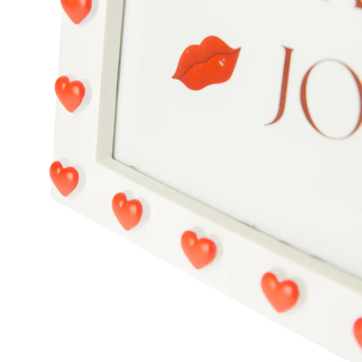 Dettaglio di una cornice rettangolare portafoto. Bordo bianco con cuori in rilievo rossi. All'interno stampa con scritto more art more joy. Sfondo bianco