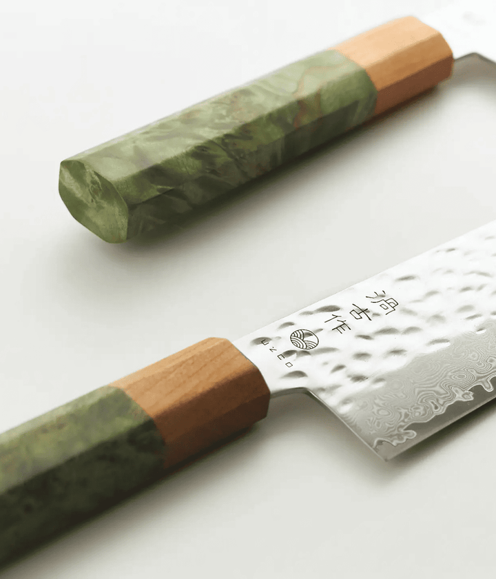 Dettaglio lama lavorata Tsuchime con scritta giapponese e manico verde in legno. Sfondo bianco
