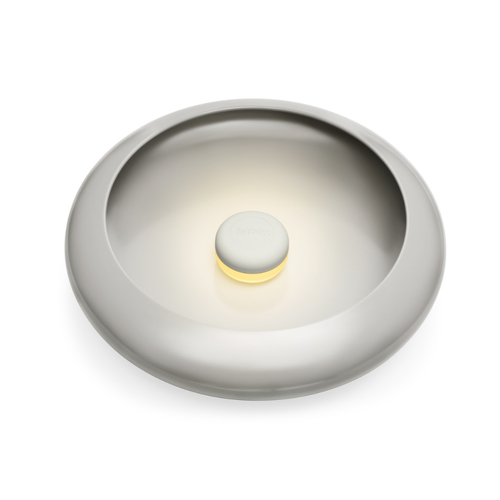 Lampada da tavolo/ svuotatsche rotonda beige con luce accesa al centro. Sfondo bianco